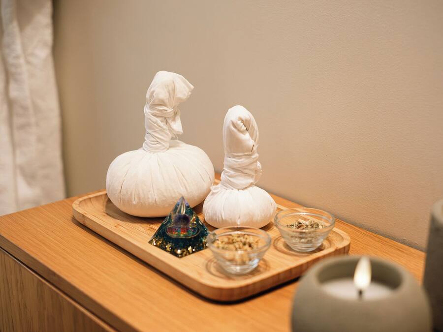 A wooden tray with two white objects resembling dolls, a small decorative item, and two glass bowls with contents on a wooden surface.
