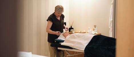 Een klinische omgeving met een patiënt die in bed ligt, een medisch professional die voor hen zorgt, en een witte beker met de naam 'Adelaide' op een tafel.