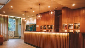 A modern reception area with wooden paneling, a reception desk, and pendant lighting. - Adelaide Hotel (Terras de Bouro)
