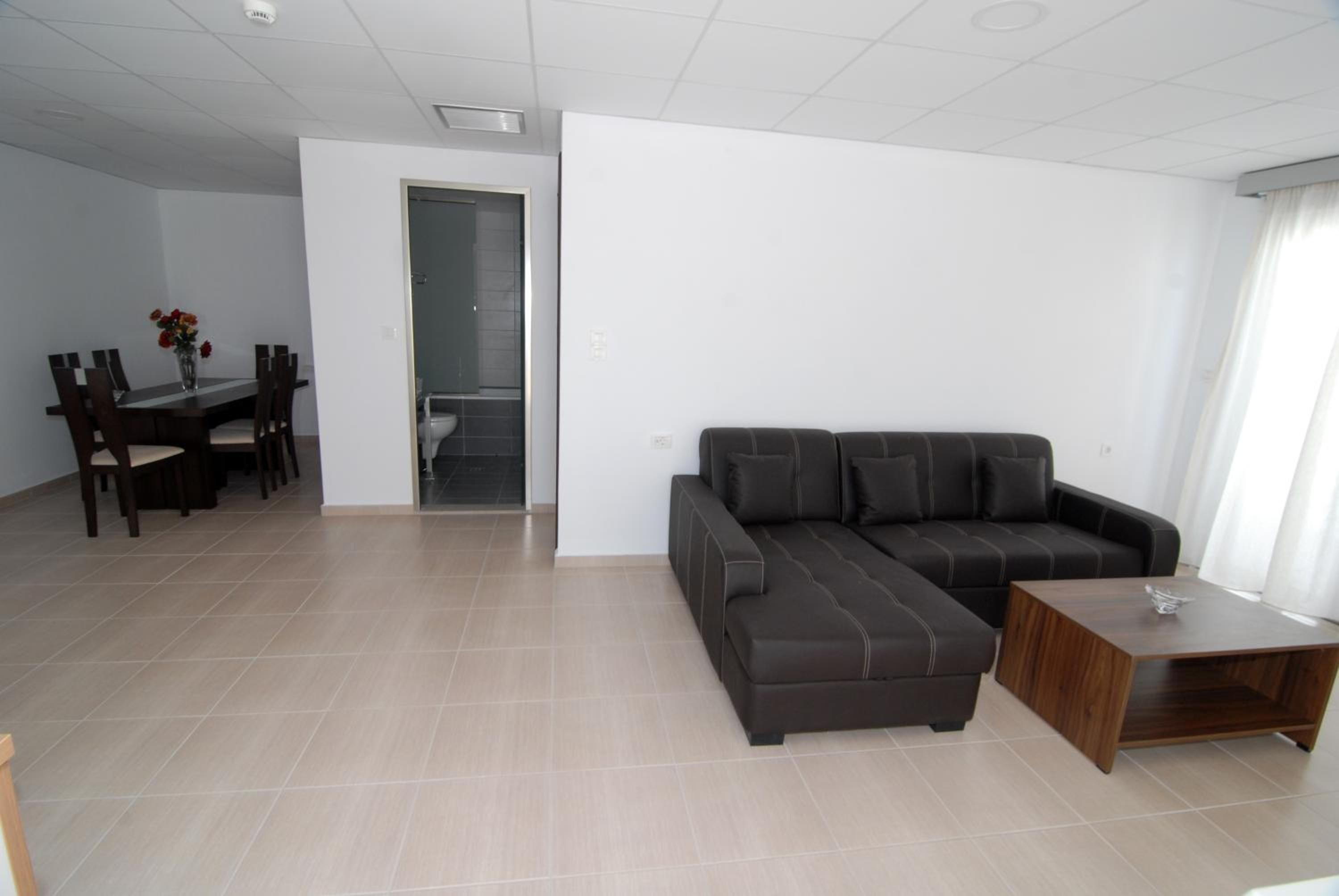 A modern living room with a sectional sofa, a dining table with chairs, and a small wooden coffee table.