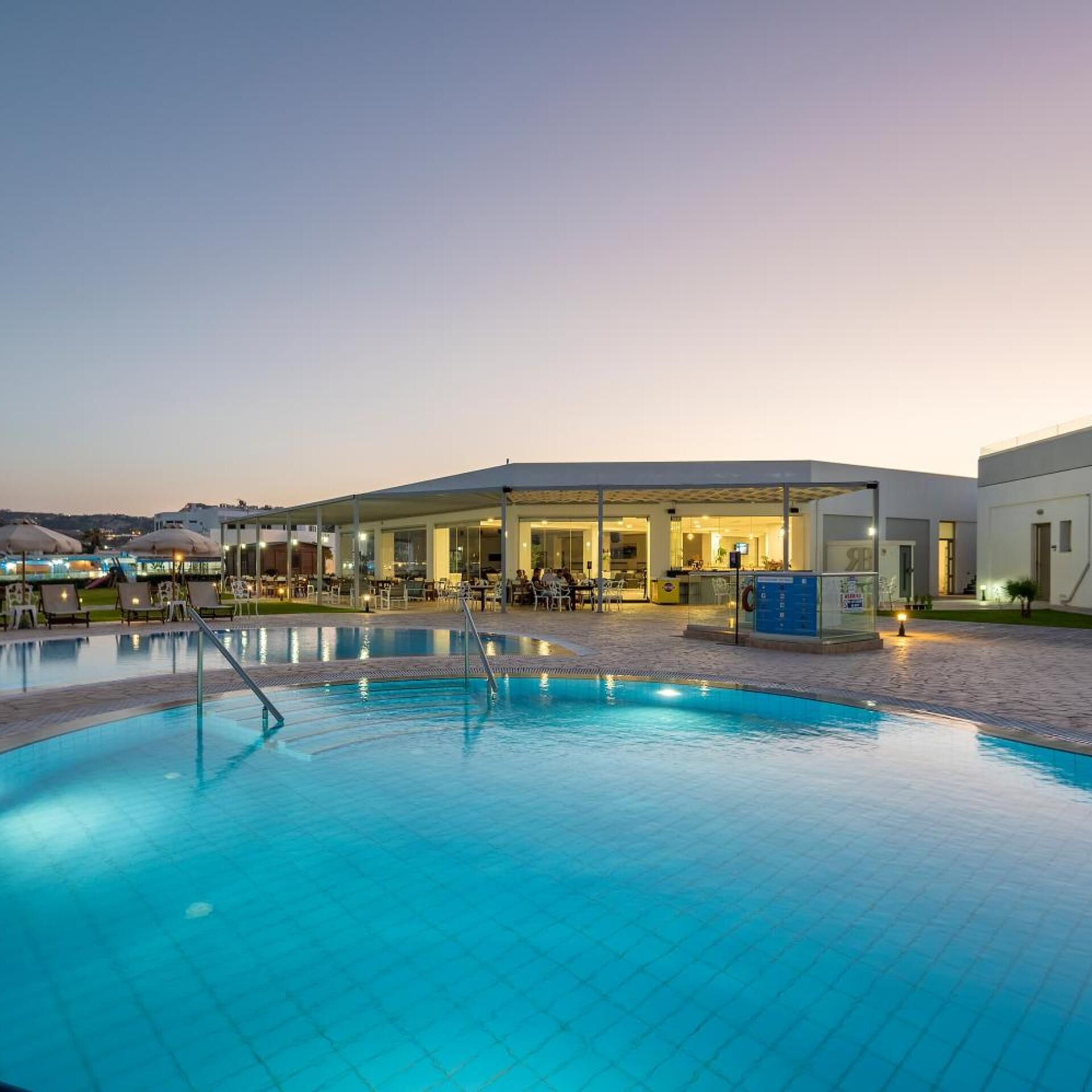 Une piscine dotée de chaises longues et d’un espace abrité, probablement faisant partie d’un hôtel ou d’un complexe touristique.