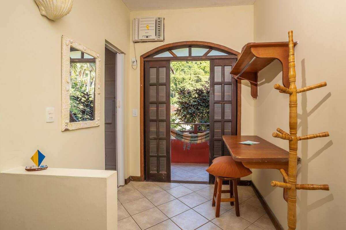 A room with a wooden table, a hammock, and a wooden coat rack.
