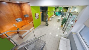 A modern hotel lobby with a staircase, seating area, and a green wall with artwork. - Boji (Las Palmas de Gran Canaria)