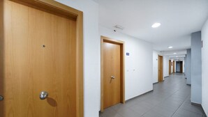 A corridor with wooden doors, white walls, and tiled flooring. - Boji (Las Palmas de Gran Canaria)