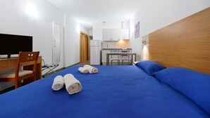 A hotel room with a bed, a desk, a chair, a television, and a kitchenette. - Boji (Las Palmas de Gran Canaria)