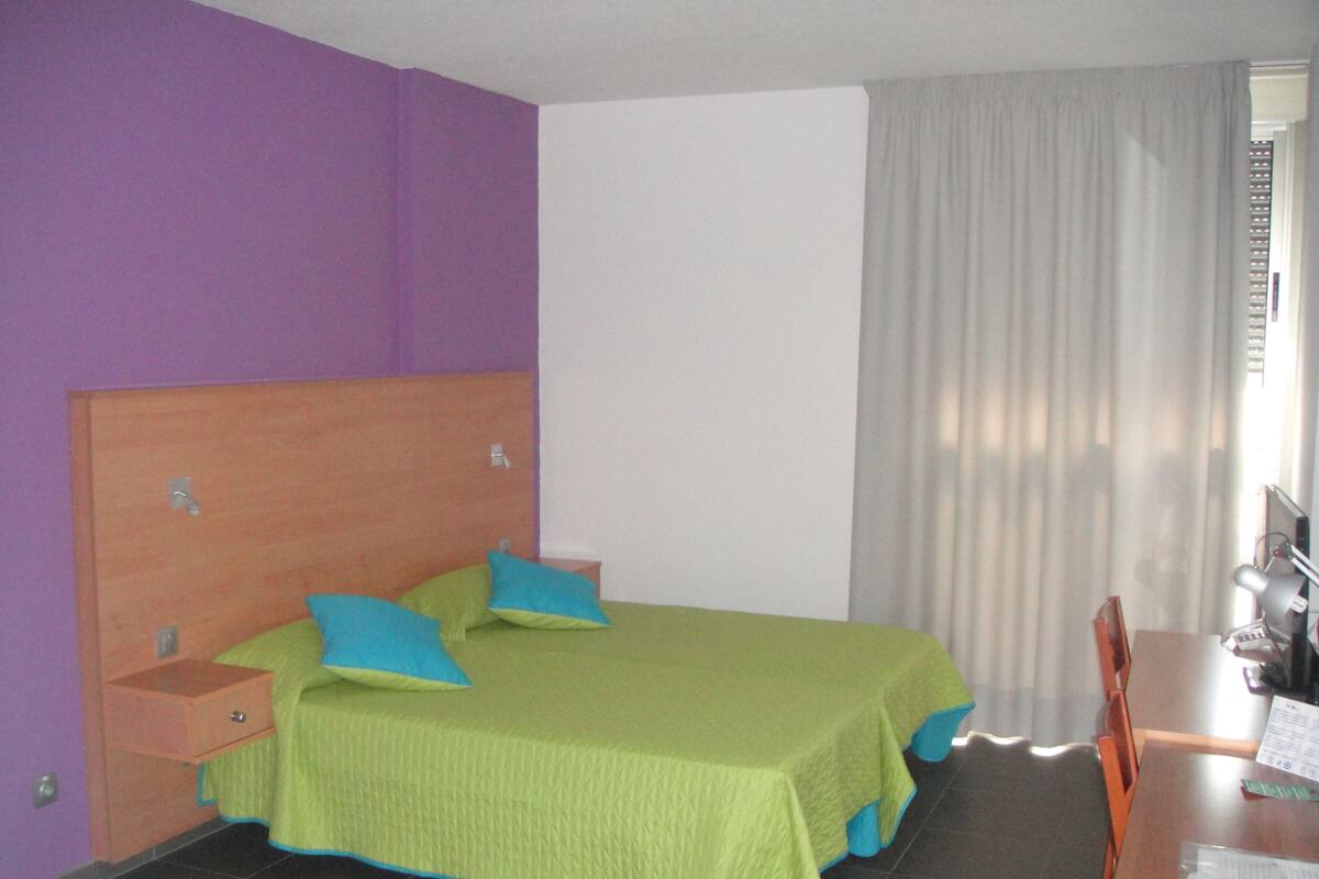 Hotellihuone, jossa on sänky, työpöytä ja tuoli.