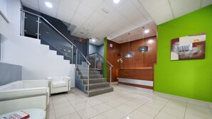 A lobby with a staircase, a reception desk, a white sofa, and a green wall. - Boji (Las Palmas de Gran Canaria)