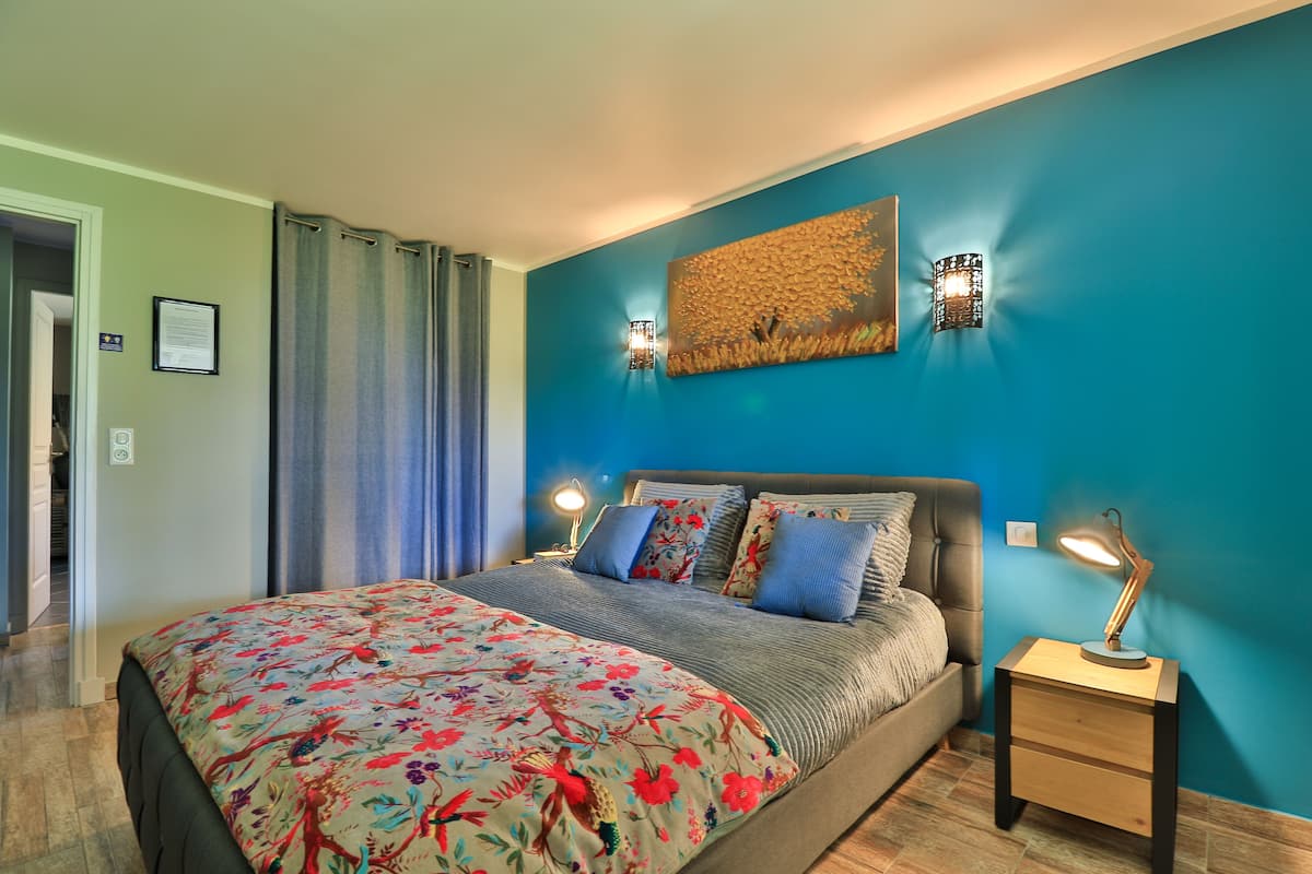 Un dormitorio con cama, mesita de noche, lámpara de pared y un adorno en la pared.