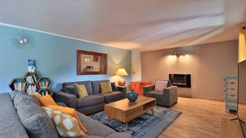 A modern living room with a grey sofa, a wooden coffee table, and a bookshelf.