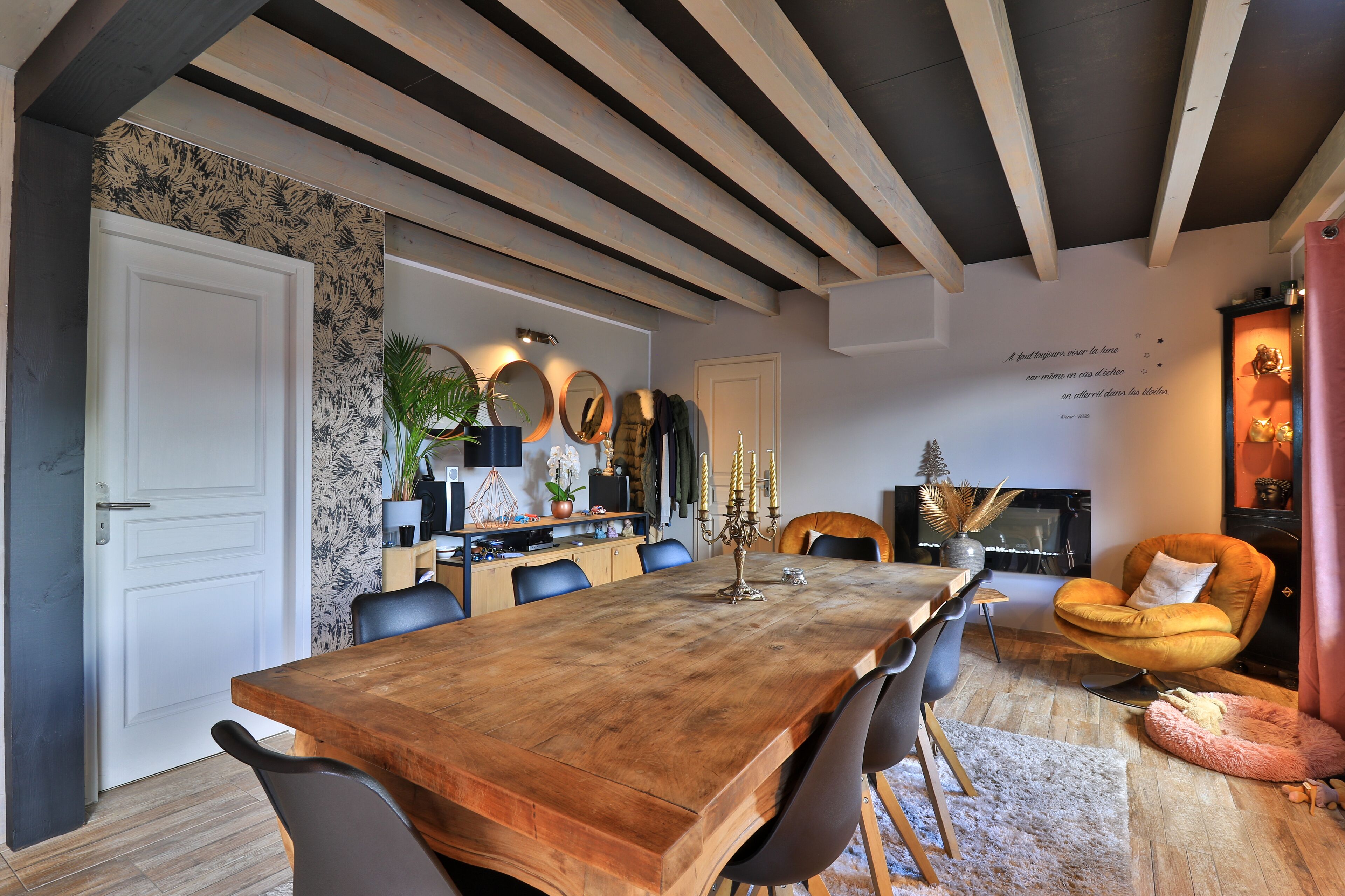 A dining area with a wooden table, black chairs, and a fireplace.