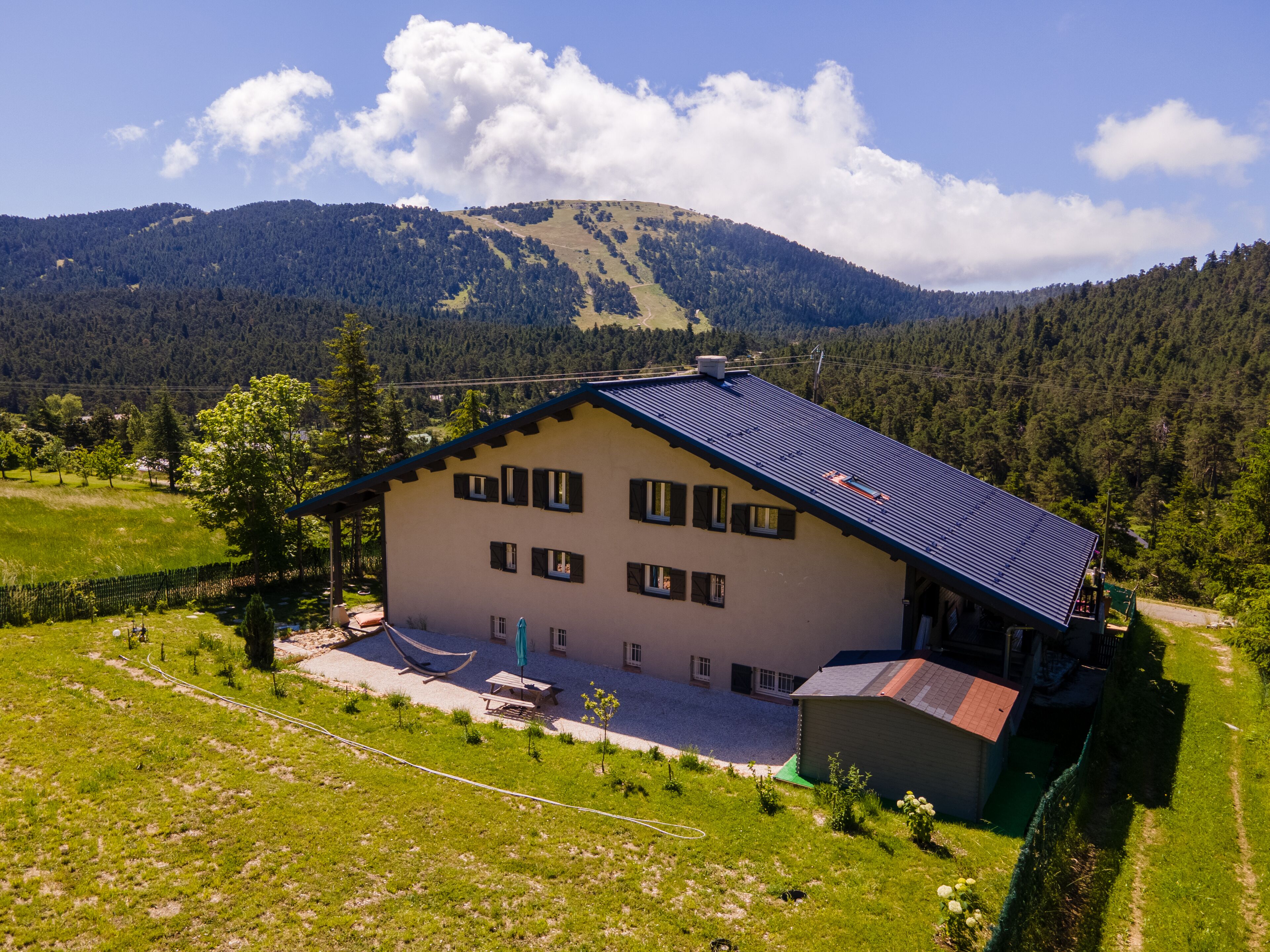 A two-story building with a sloped roof, a fenced yard, and a view of a mountainous landscape.