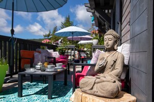 Una estatua de Buda en un jardín con mobiliario exterior y sombrillas.