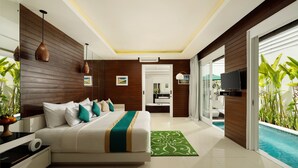 A modern hotel room with a large bed, a green patterned rug, a TV, and a view of a swimming pool. - Bajra Bali Villa (Seminyak)