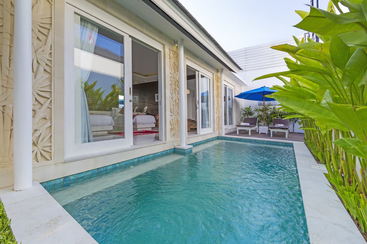A swimming pool with a clear blue water, surrounded by a white tiled deck.