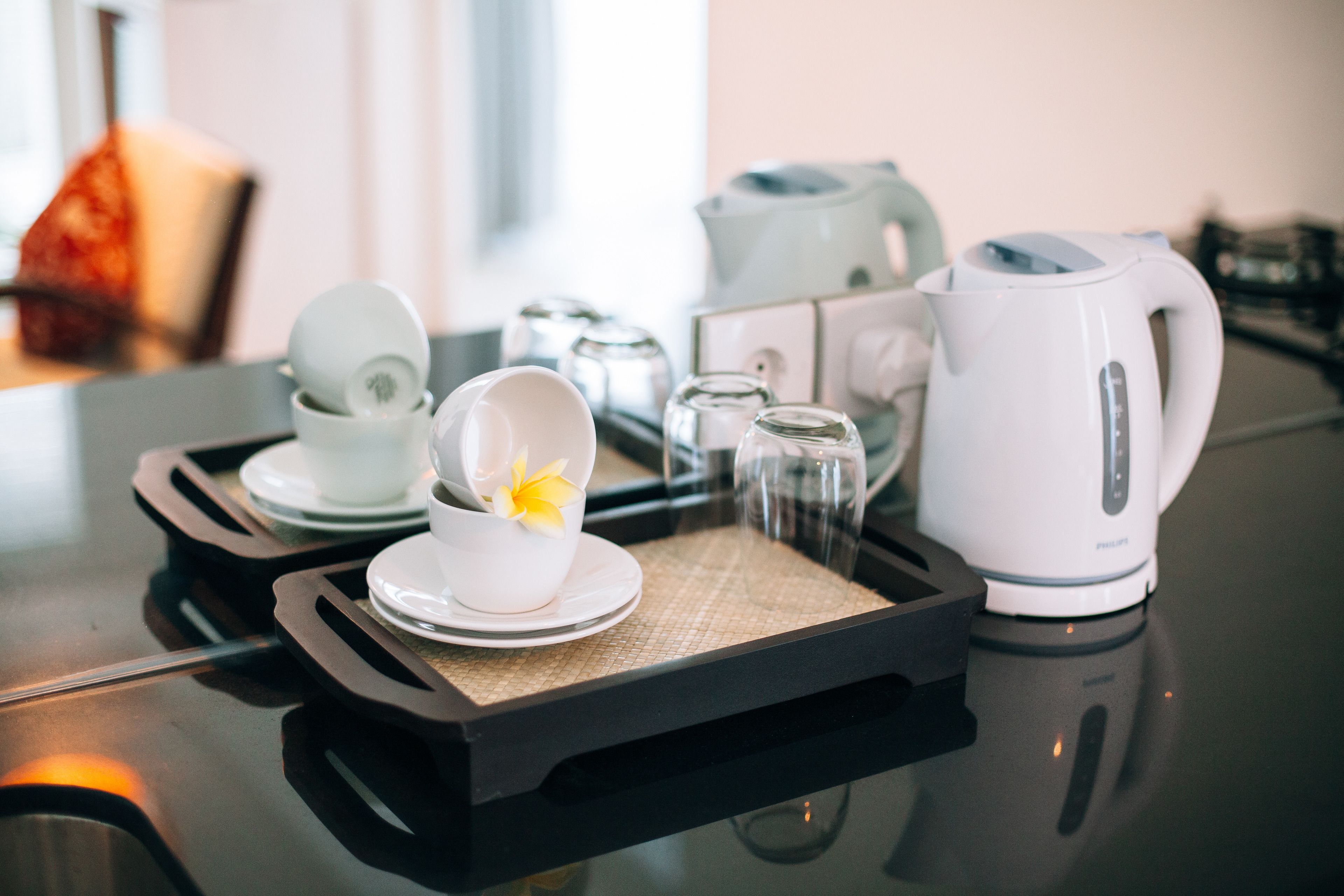 A tray with a white coffee maker, a white teapot, and a white cup with a yellow flower.