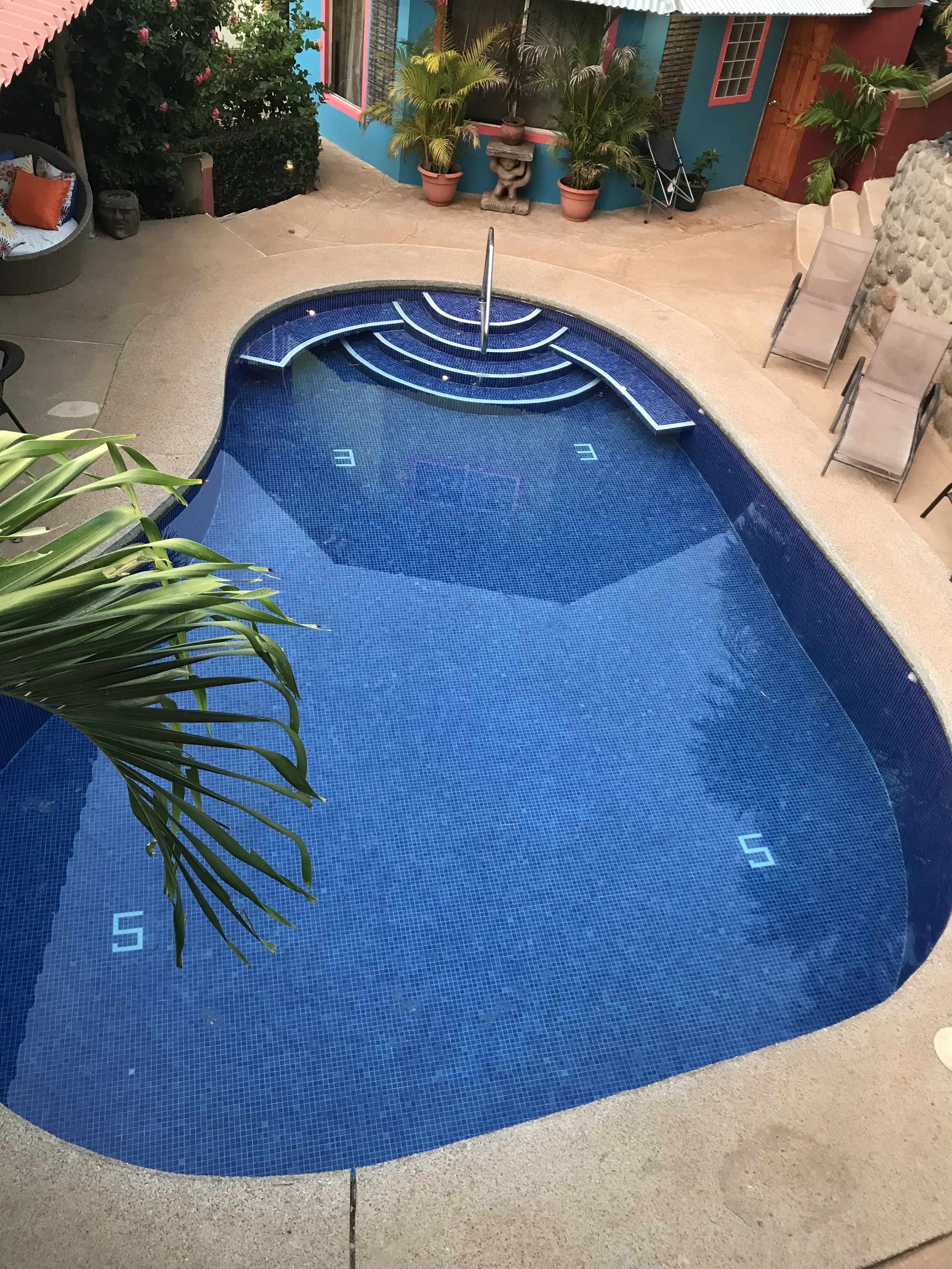 Una piscina con suelo de azulejos azules y una fuente central.