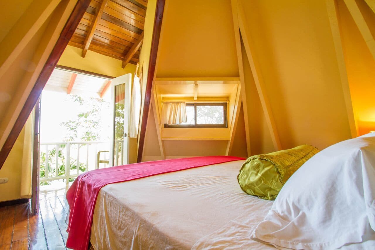 A bedroom with a bed, a window, and a balcony.
