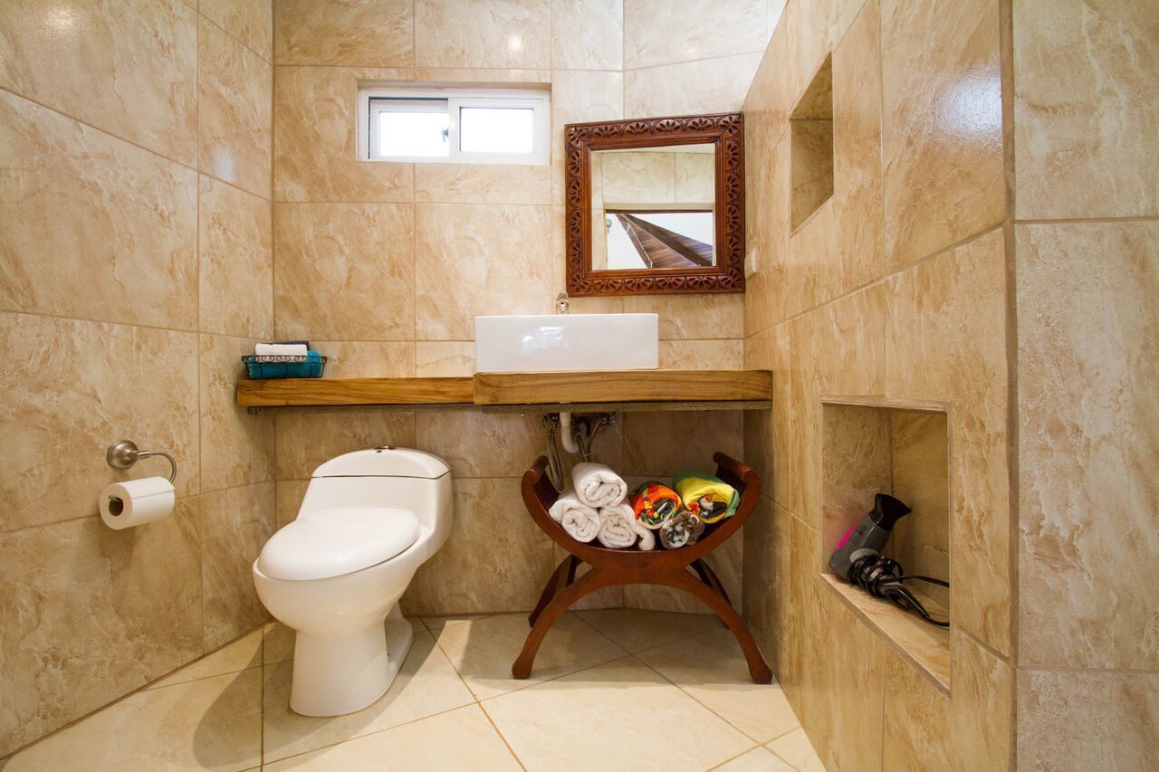 A bathroom with a toilet, sink, and mirror.