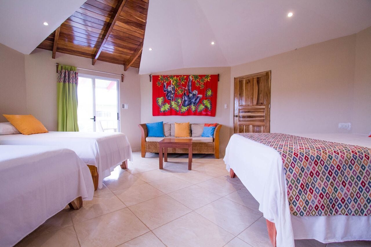Una habitación de hotel con dos camas, un sofá, una mesa y un tapiz colorido.