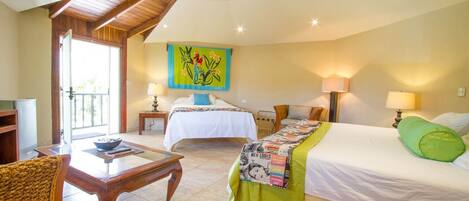 A hotel room with two beds, a wooden ceiling, a dining table, and a view of the outdoors.