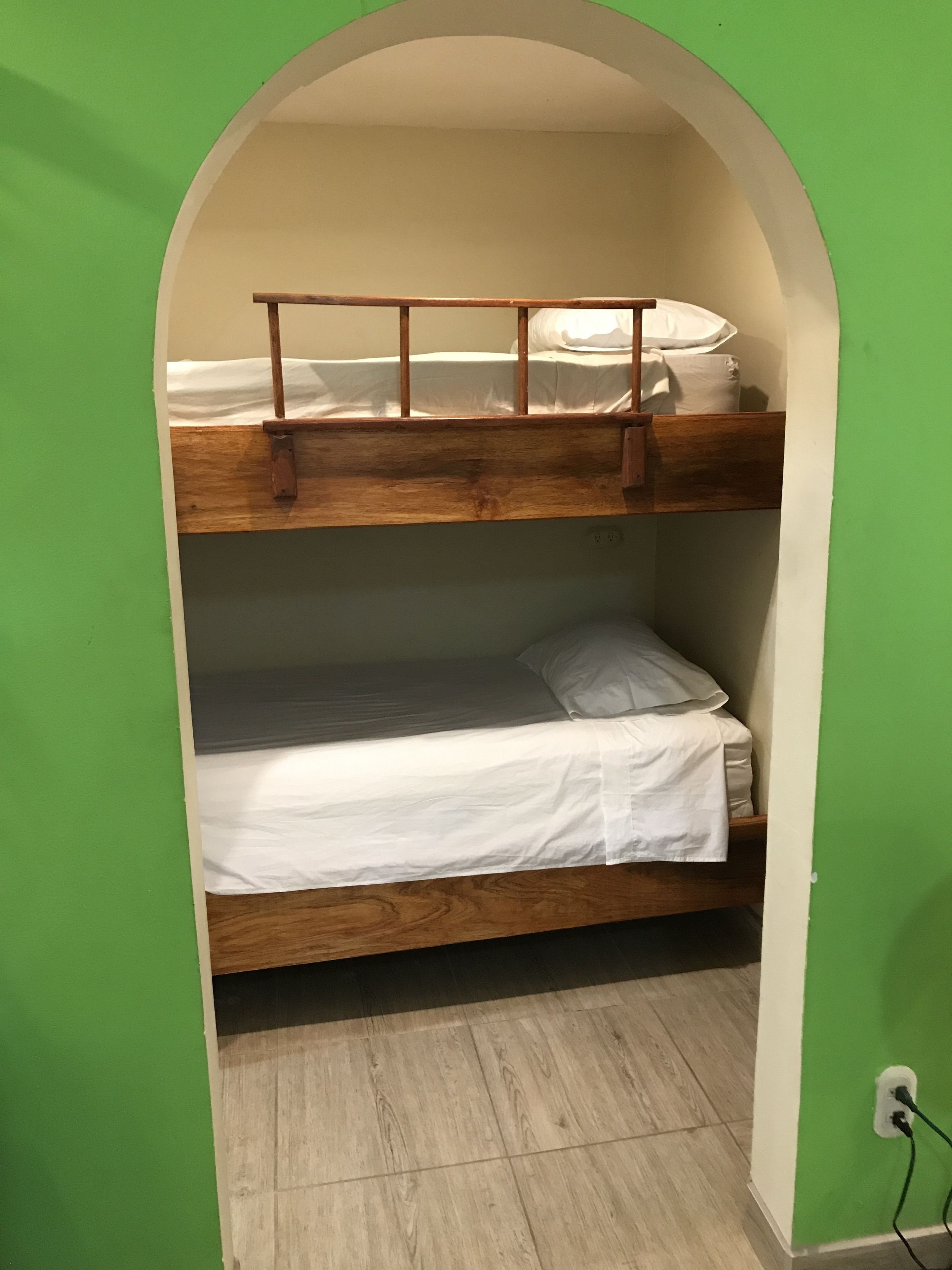 Une chambre avec des lits superposés, des murs verts et un plancher en bois.