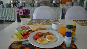 Une table de petit-déjeuner avec des œufs, des tomates, du pain et du jus.