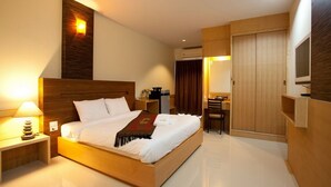 Une chambre d’hôtel moderne avec un lit en bois, une table de chevet avec une lampe, un bureau avec une chaise et un téléviseur fixé au mur.