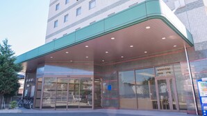 A hotel entrance with a covered entrance area, large glass doors, and a visible parking lot. - Ariston Inn Kanda Kitakyushu Airport (Kanda)