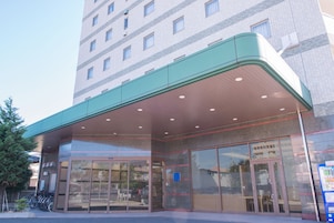 A hotel entrance with a covered entrance area, large glass doors, and a visible parking lot.