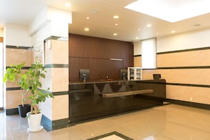 A reception area with a black reception desk, a potted plant, and a wooden panel wall.