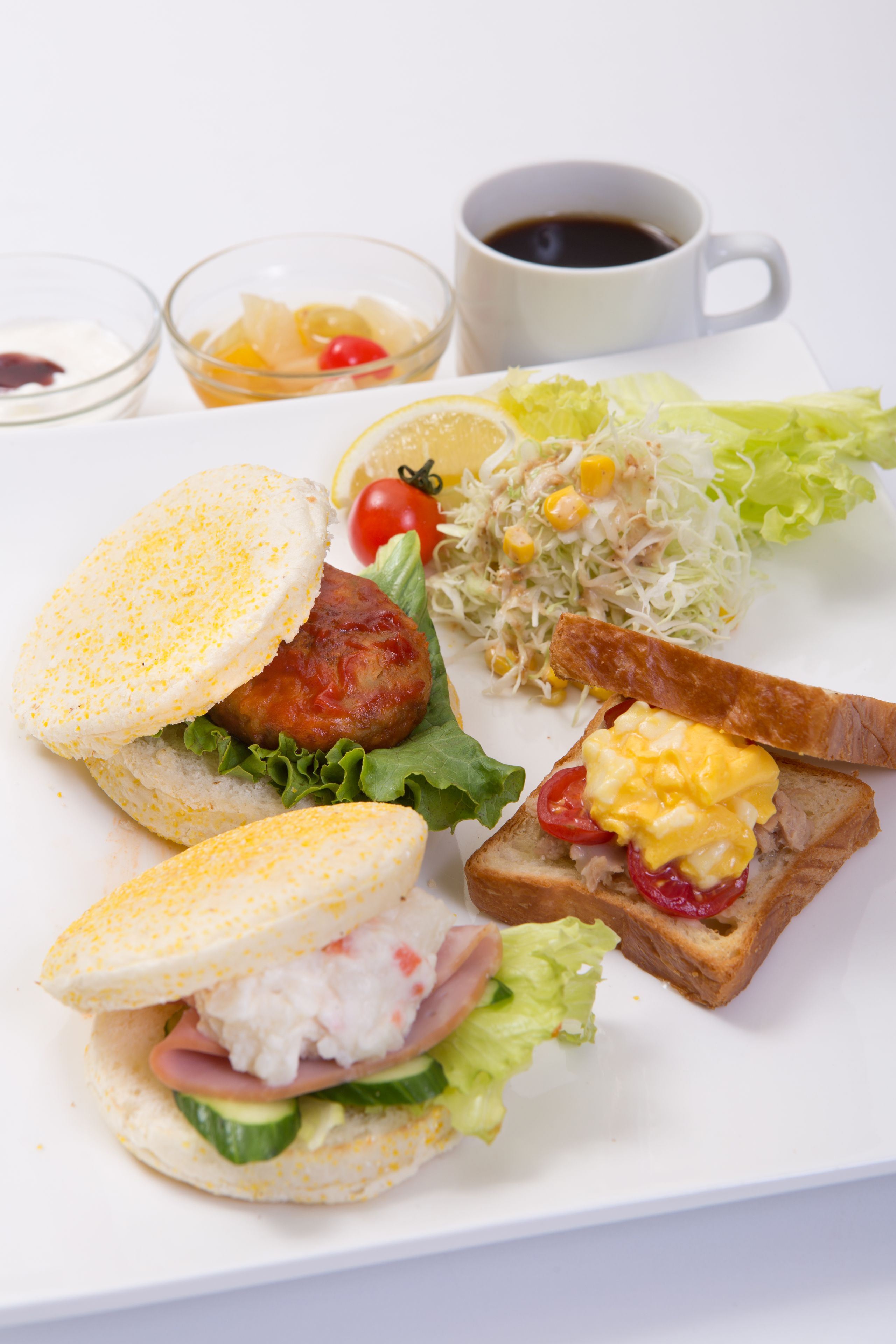 Ein Teller mit Sandwiches, einem Salat und einer Tasse Kaffee.