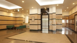 A spacious lobby with a reception desk, seating area, and an elevator. - Ariston Inn Kanda Kitakyushu Airport (Kanda)