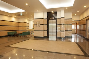 A spacious lobby with a reception desk, seating area, and an elevator.