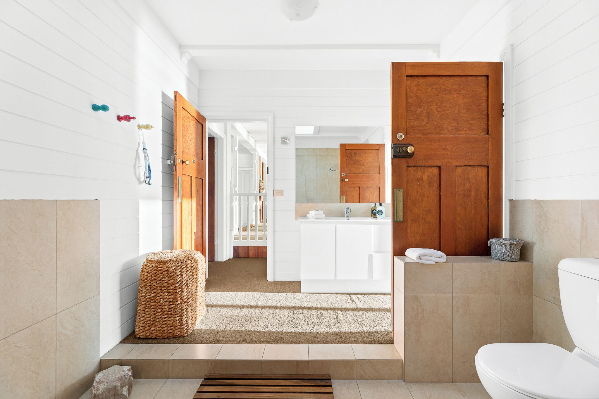 Een moderne badkamer met een houten deur, een witte wastafel en een douchecel.