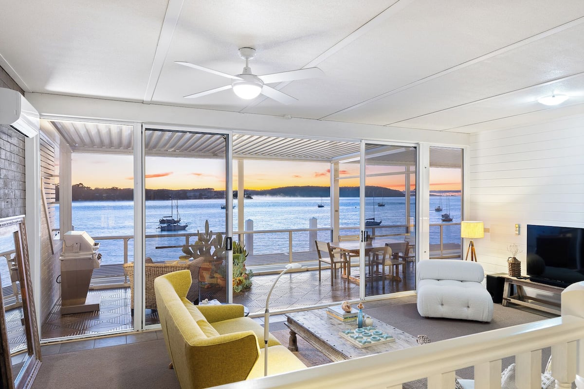 A spacious living area with a large sliding glass door leading to a balcony overlooking a body of water.