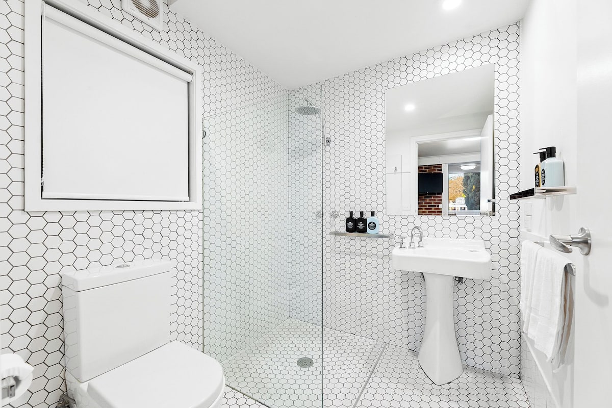 A bathroom with a hexagonal tile pattern, a toilet, a sink, and a shower area.
