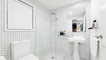 Un baño con un patrón de baldosas hexagonales, un inodoro, un lavabo y una zona de ducha.