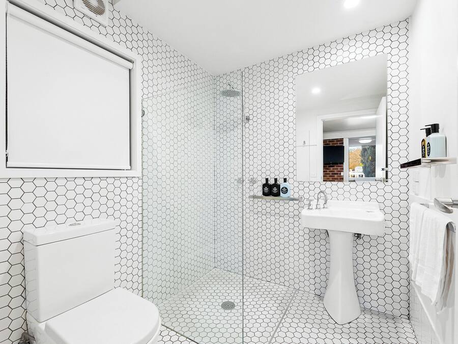 Un baño con un patrón de baldosas hexagonales, un inodoro, un lavabo y una zona de ducha.