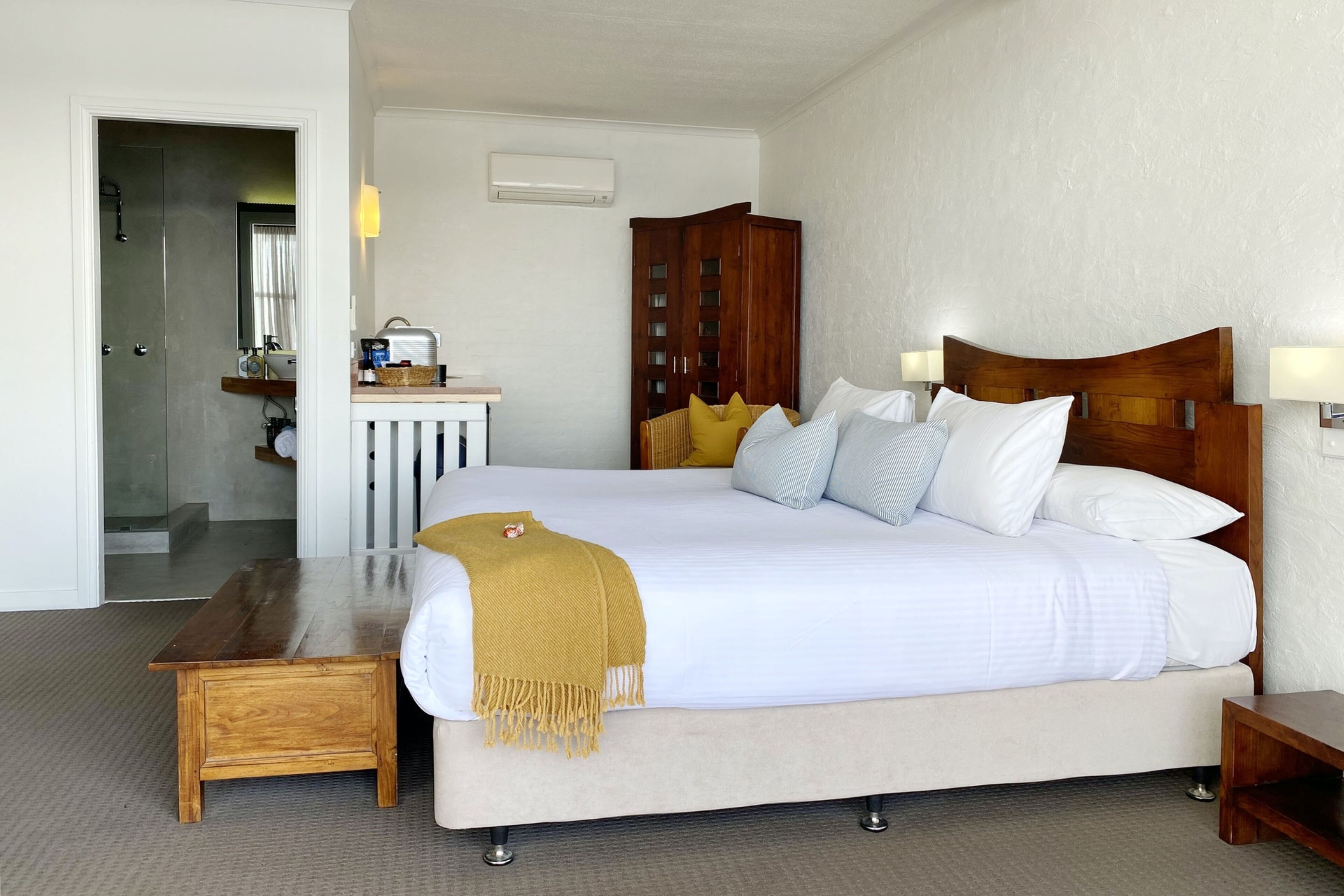 A neatly arranged hotel room with a large bed, bedside tables, a wooden bench, and a wardrobe.