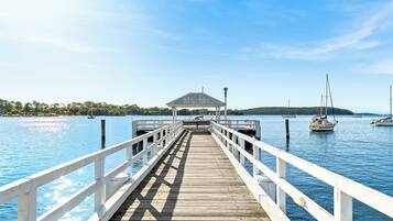 A wooden pier leading to a gazebo over water with boats.