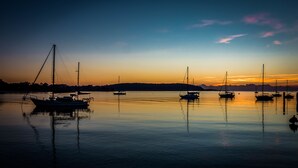 Une étendue d’eau calme où plusieurs bateaux sont amarrés, un ciel dégagé et une terre ferme visible au loin.