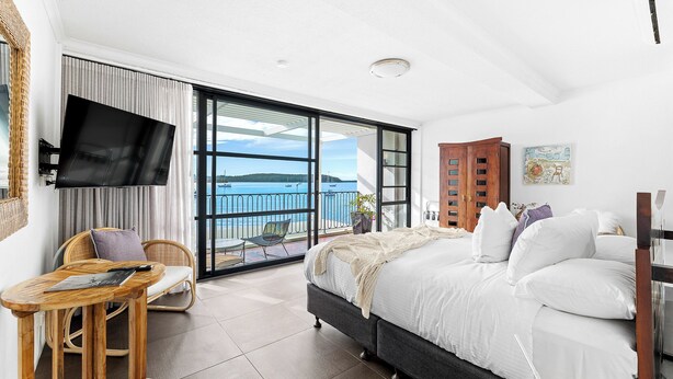 Une chambre avec un lit, une télévision, une chaise, une table et une vue sur la mer.