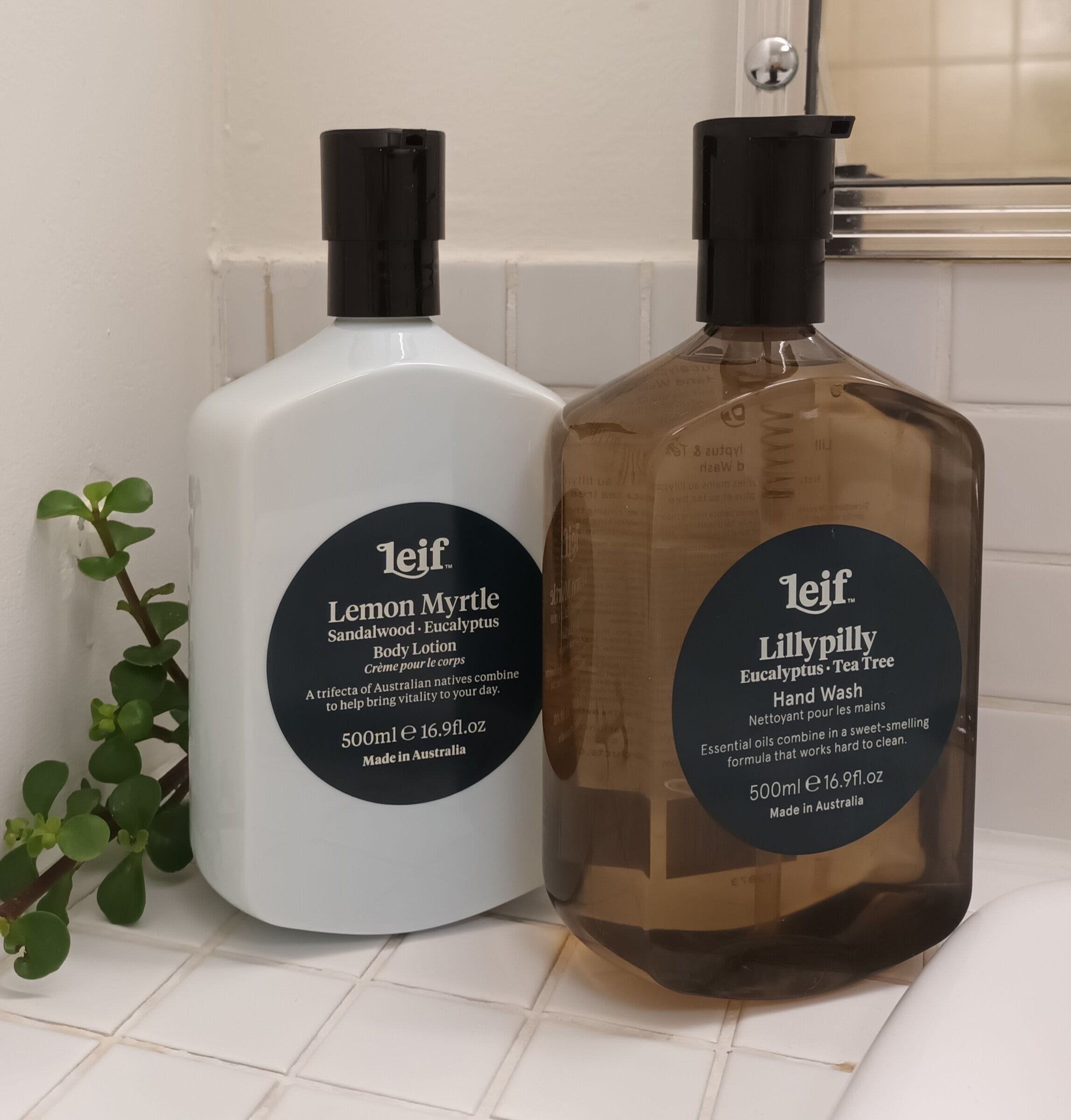 Two bottles of Leif body lotion and hand wash on a white tiled surface.