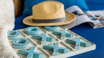 A board game with blue and red pieces, a straw hat, and a magazine on a blue surface.