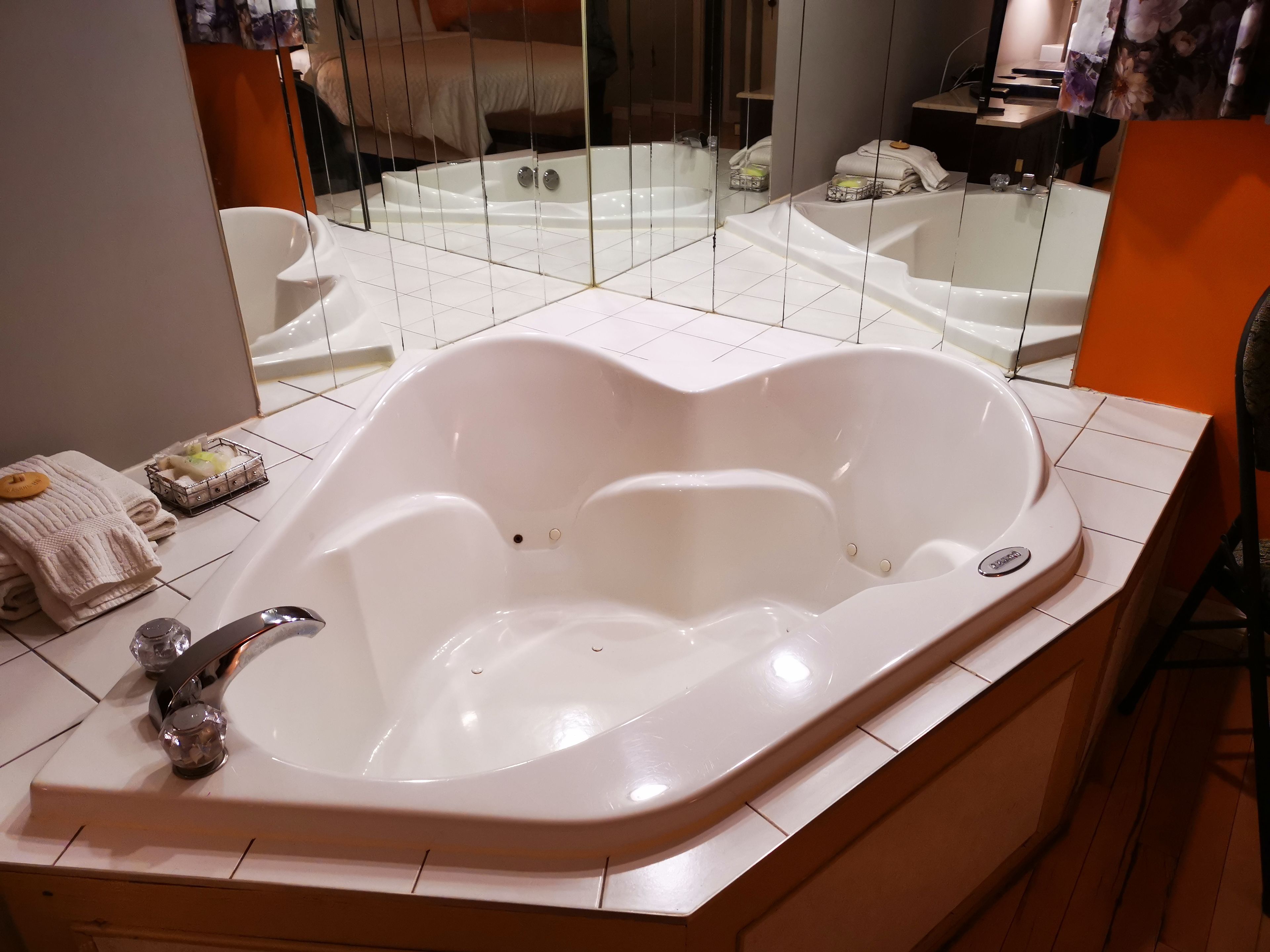 Un baño moderno con una bañera independiente grande, un espejo y una pequeña zona de estar.