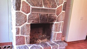 A stone fireplace with a vent, surrounded by red tiles. - Motel Tremblant (Mont-Blanc)