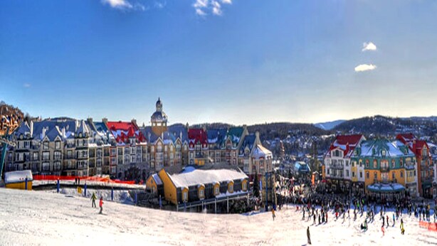 A snow-covered ski resort with colorful buildings and a large crowd of people. - Motel Tremblant (Mont-Blanc)