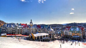 Estación de esquí nevada con edificios coloridos y una gran multitud de personas.