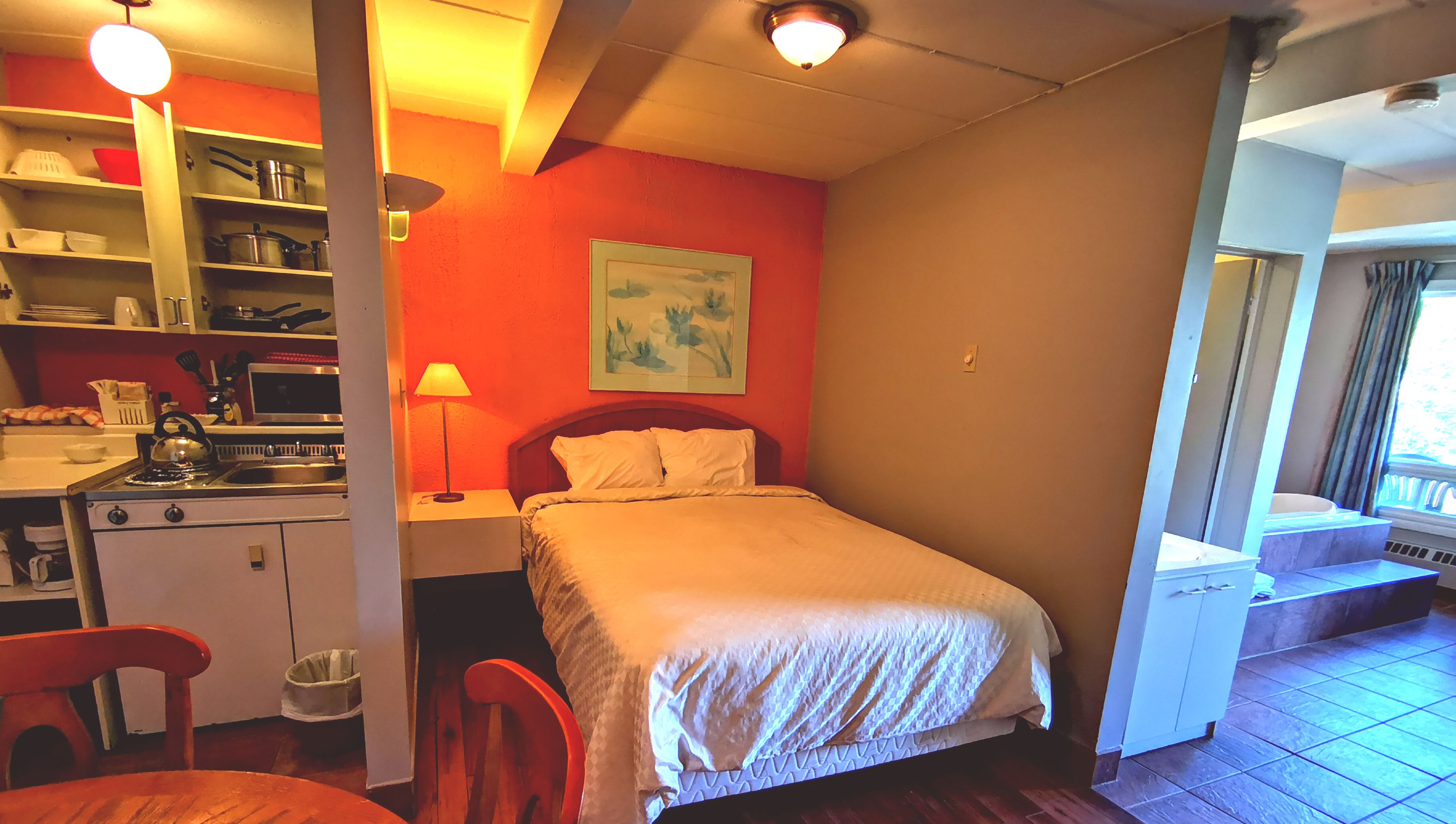 Een compacte kamer met een bed, een kitchenette en een kleine eethoek.