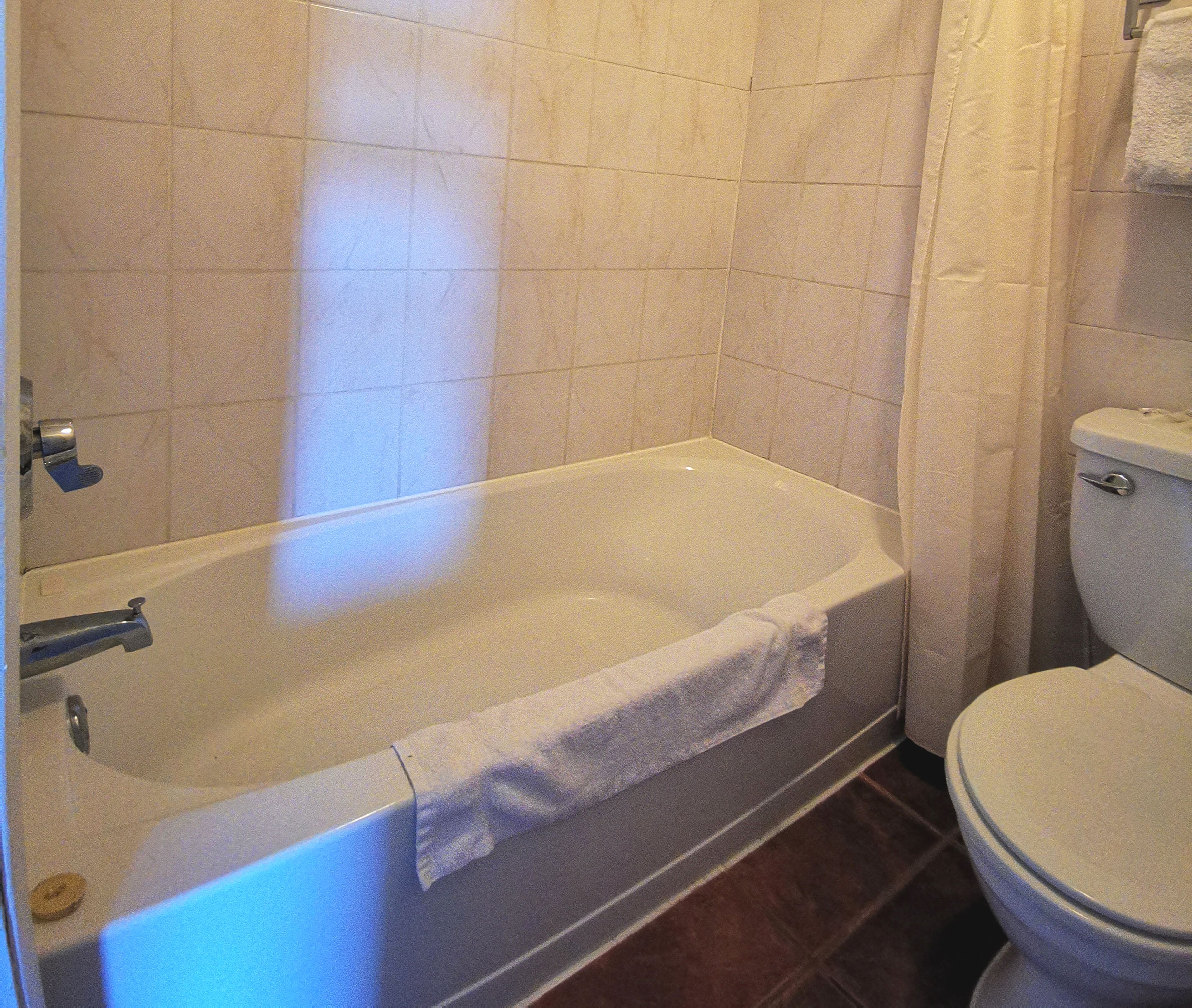 Une salle de bain avec une baignoire, des toilettes et des murs carrelés.